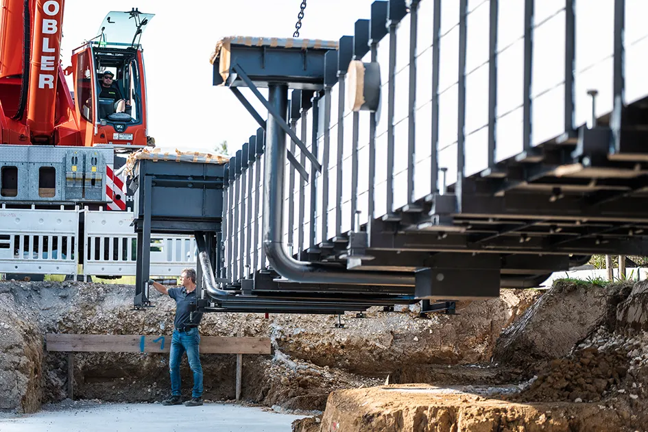 Montage einer truckcon Stahlfertiggrube auf einer Baustelle. Die Aufnahme zeigt das präzise Einheben der vormontierten Werkstattgrube in die vorbereitete Baugrube mittels Krantechnik.